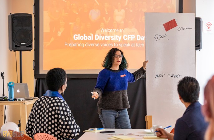 Kathryn in front of a whiteboard with "good" and "not great". In background "Welcome to Global Diversity CFP Day"