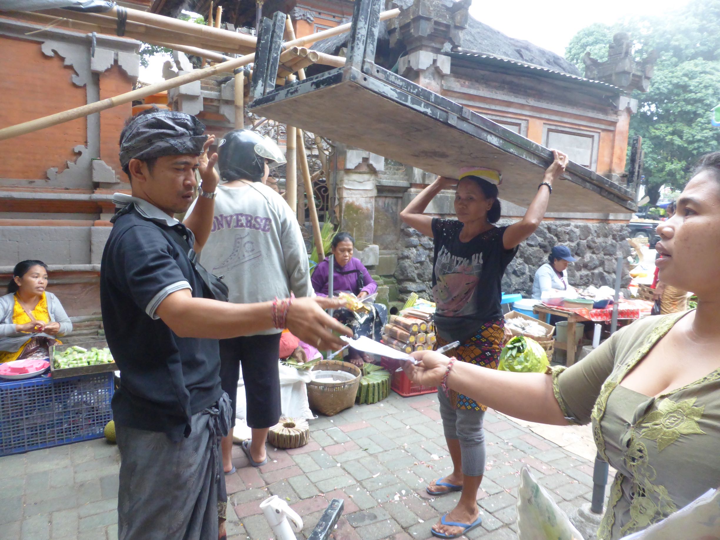 transaction in foreground, woman with table on head in bg